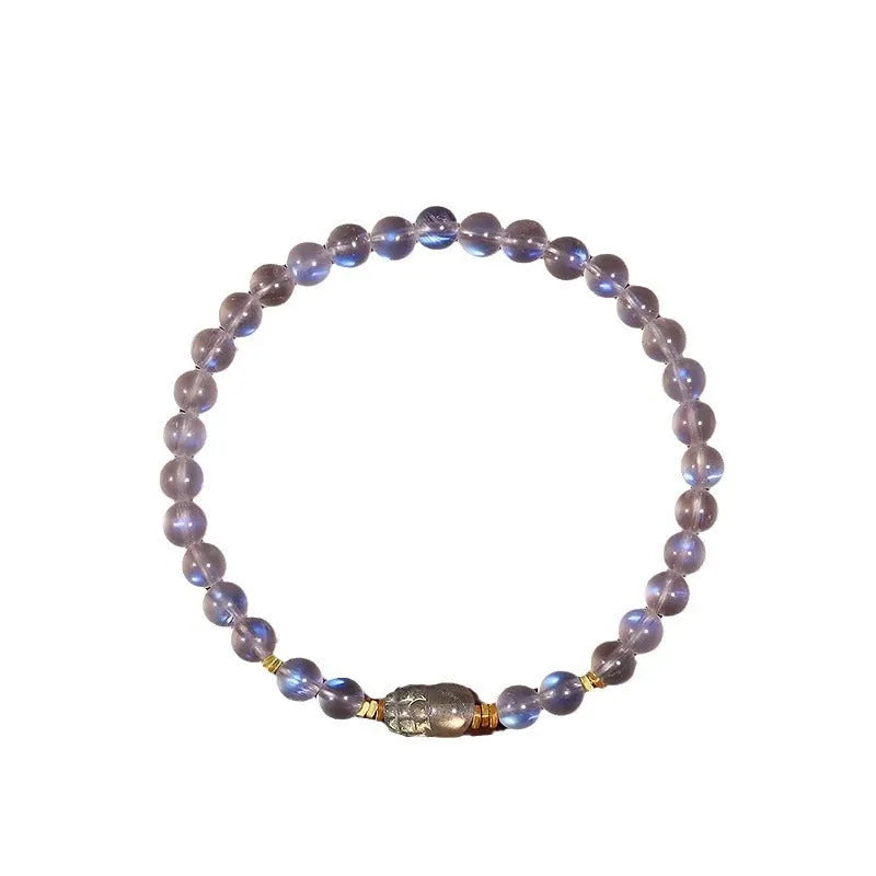 Close-up of a women's moonstone bracelet with an animal or Zodiac motif on a blue background.