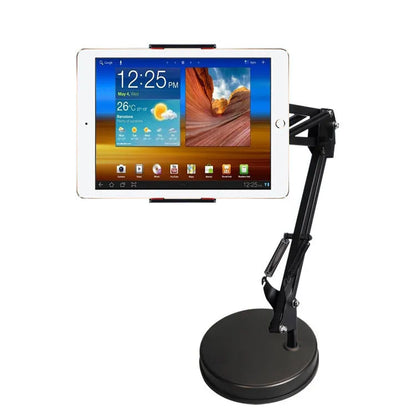 Black metal adjustable phone and tablet stand with a heavy round base on a wooden desk