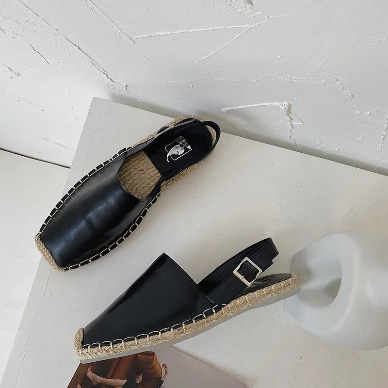 Women's flat canvas fisherman sandals in black, shown from the side on a white background.