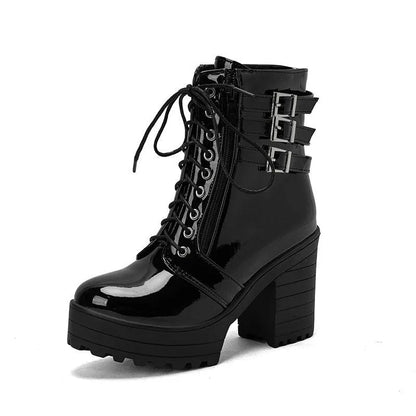 Women's black chunky heel ankle boots with round toe and front lace-up on a wooden floor.