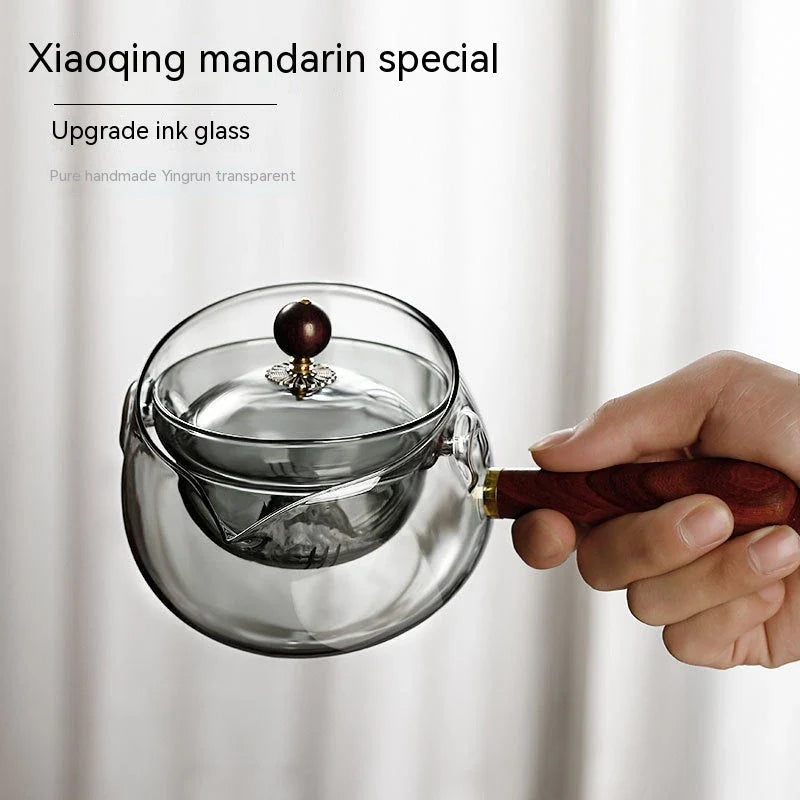 Elegant rotating glass teapot with wooden handle for a flavorful and visually appealing tea brewing experience