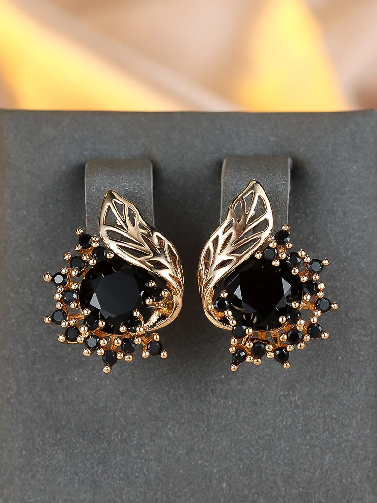 Rose gold plated women's stud earrings with a round flower shape, feather detail, and a central cubic zirconia stone.