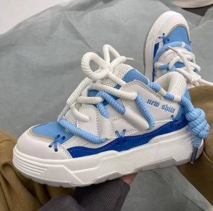 Women's grey thick-soled retro sneakers with lace-up front and chunky rubber platform sole on a wooden floor.