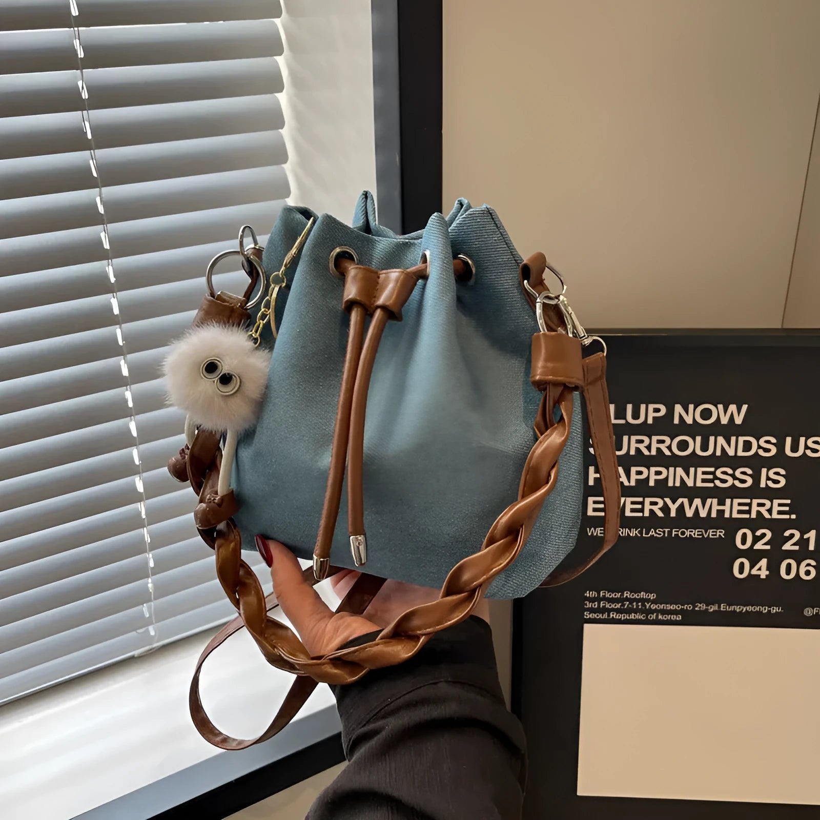 Blue cross body bucket bag with synthetic leather lining and adjustable shoulder strap