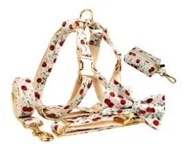 Red cherry printed dog collar with light gold buckle and matching leash, bow, vest and poop bag holder set