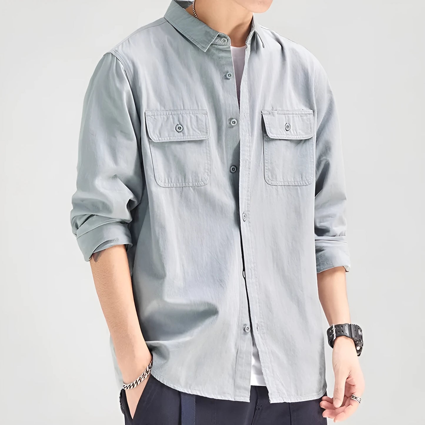 Man wearing a loose-fit grey cardigan-style overalls shirt with long sleeves.