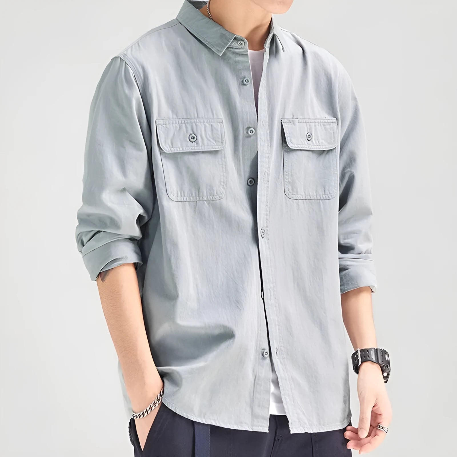 Man wearing a loose-fit grey cardigan-style overalls shirt with long sleeves.