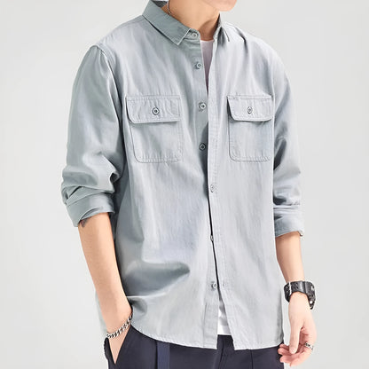 Man wearing a loose-fit grey cardigan-style overalls shirt with long sleeves.