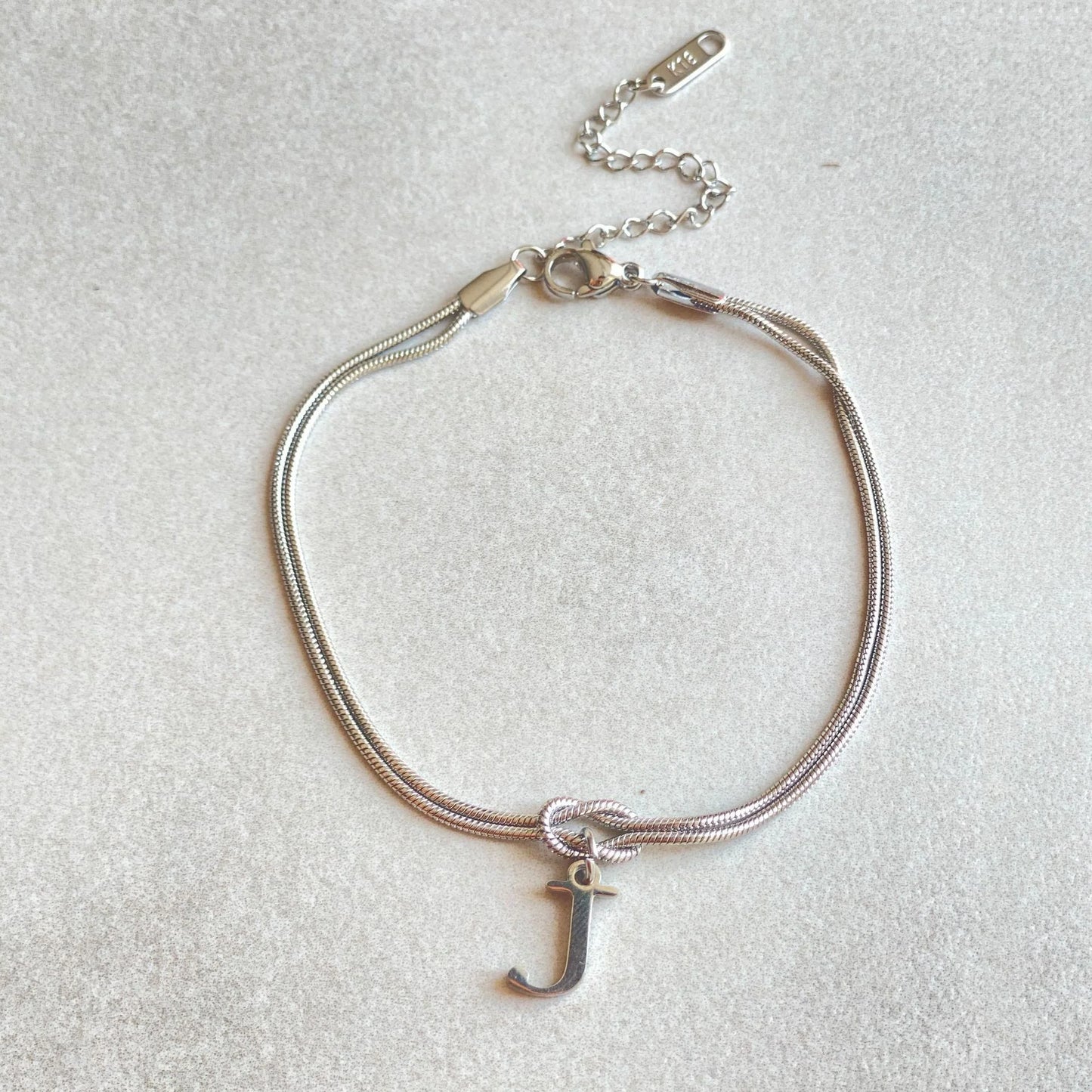 Elegant letter charm bracelets for women in gold and silver tones, featuring a delicate snake chain design and personalised letter charms.
