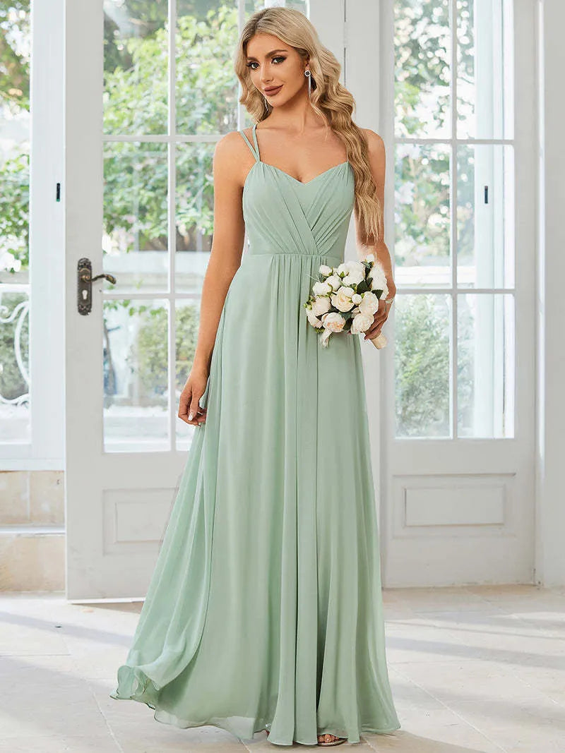 Woman wearing a light green sleeveless dress with a long pleated A-line skirt.