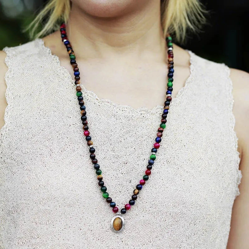 Coloured tiger-eye natural stone bead necklace and bracelet set with 108 gem-inlaid pendants on a dark background.
