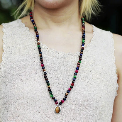 Coloured tiger-eye natural stone bead necklace and bracelet set with 108 gem-inlaid pendants on a dark background.