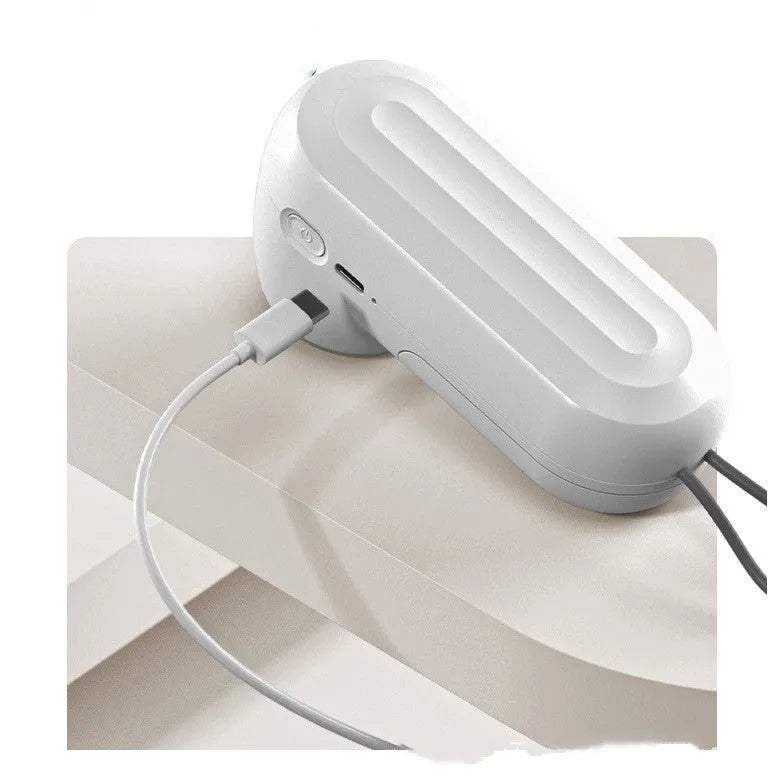 White handheld vacuum sealing machine with USB charging port on a kitchen counter.