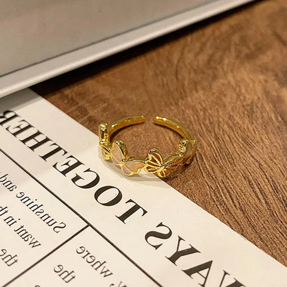 Copper butterfly women's ring with an open loop design on a plain background.