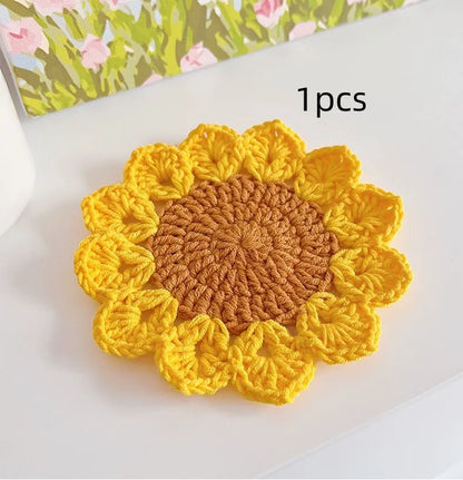 Hand-woven circular wool coaster with a flower pattern, part of a set for table protection.