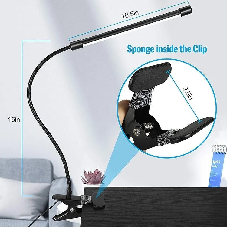Black adjustable gooseneck desk lamp with USB cable bent over a notebook on a wooden desk.