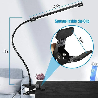 Black adjustable gooseneck desk lamp with USB cable bent over a notebook on a wooden desk.