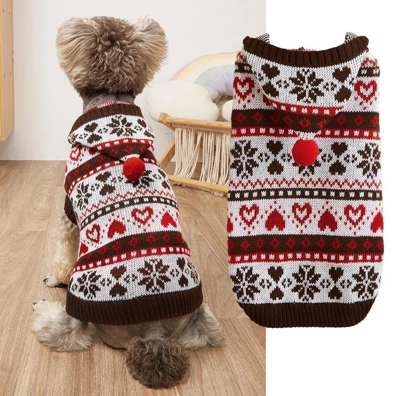 Small dog wearing a pink camouflage patterned knitted sweater with snowflake and heart stripes.