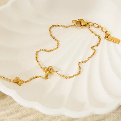 Gold stainless steel women's bracelet with geometric design of eight pointed stars and flowers.