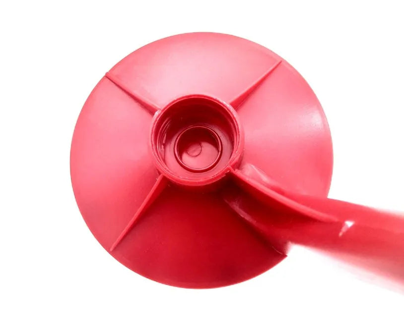 Red plastic Magic Tap soda bottle dispenser attached to an inverted 2-litre bottle on a kitchen table.