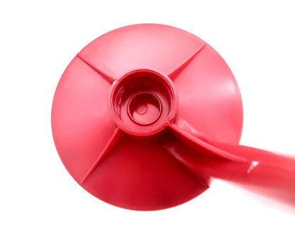 Red plastic Magic Tap soda bottle dispenser attached to an inverted 2-litre bottle on a kitchen table.