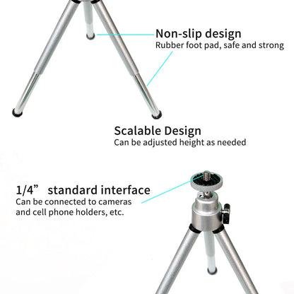 Black mini camera tripod with extended legs and a separate U-shaped universal phone clip on a table.