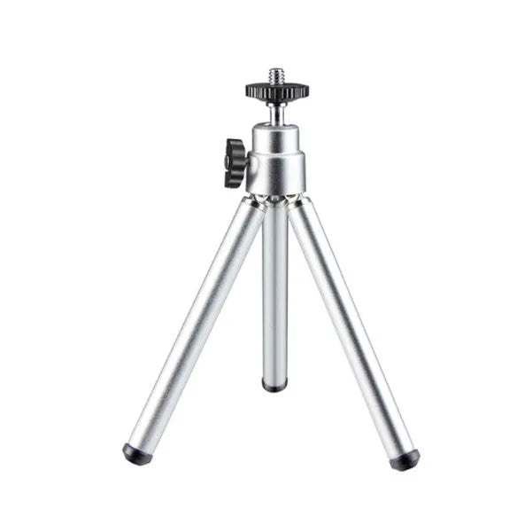 Black mini camera tripod with extended legs and a separate U-shaped universal phone clip on a table.