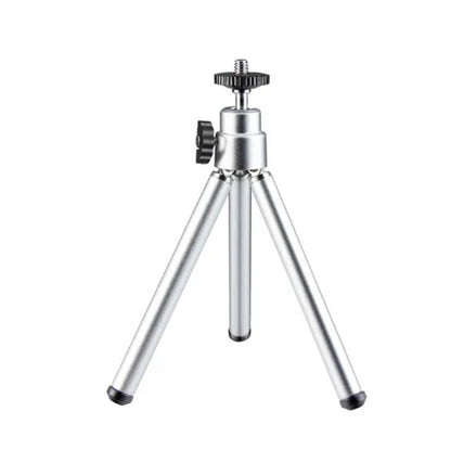 Black mini camera tripod with extended legs and a separate U-shaped universal phone clip on a table.