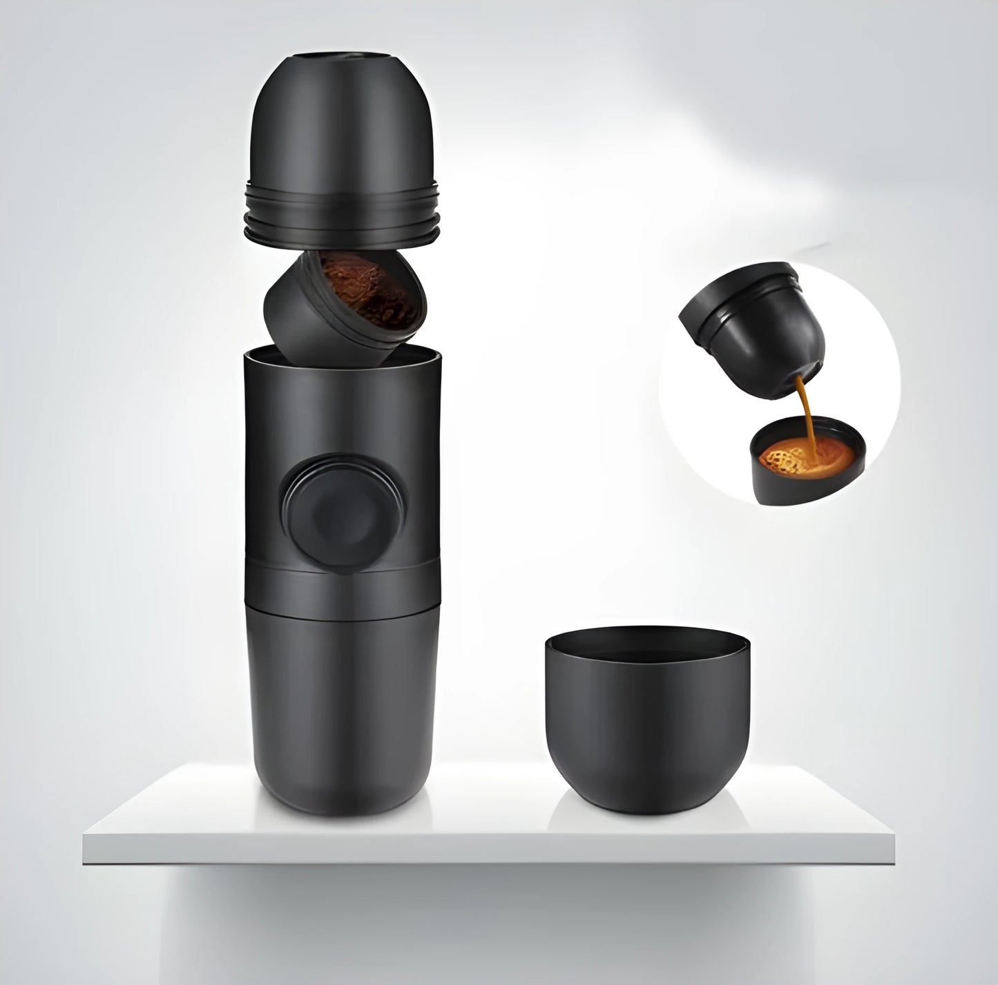 Black portable manual espresso maker with stainless steel parts, shown next to a coffee bag and mug.