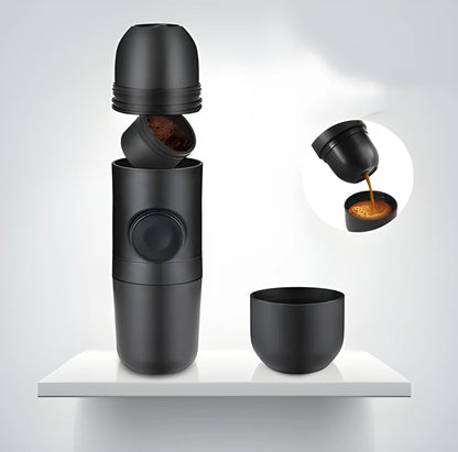 Black portable manual espresso maker with stainless steel parts, shown next to a coffee bag and mug.