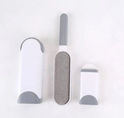 Blue reusable pet hair removal brush with double-sided head next to its self-cleaning base.