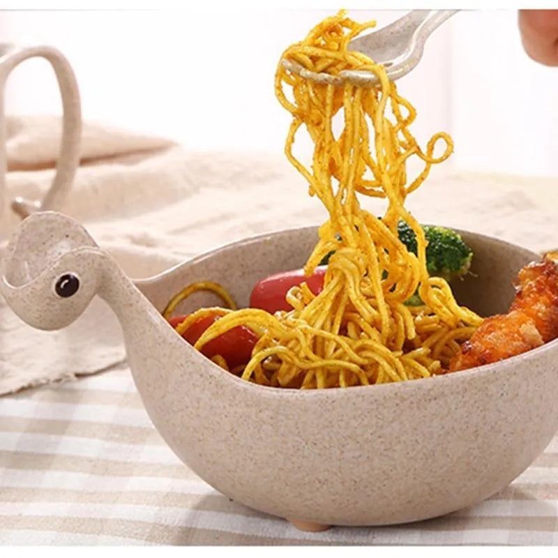 Three colourful dinosaur-shaped bowls made from wheat straw in pink, green, and beige.