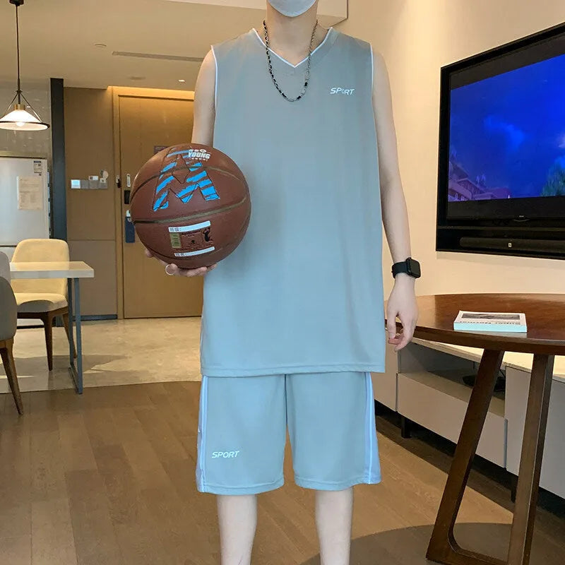 Man wearing a grey sleeveless basketball vest and matching shorts for sports.