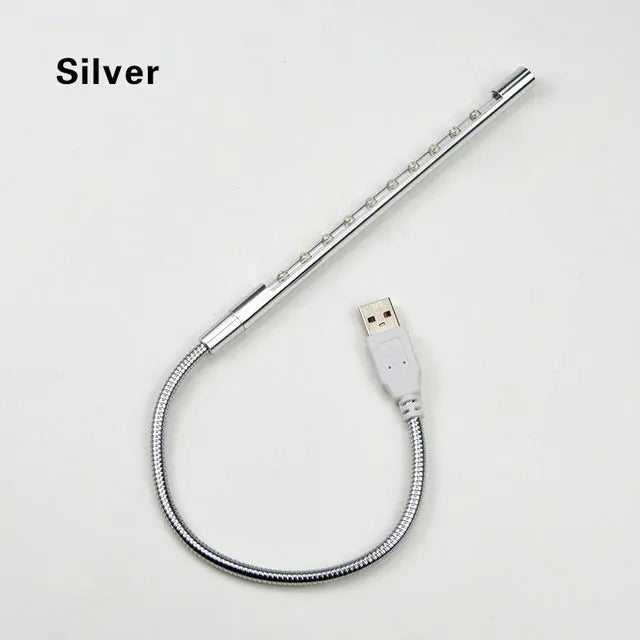 Spiral shaped silver aluminium USB LED desk lamp bent on a wooden desk.