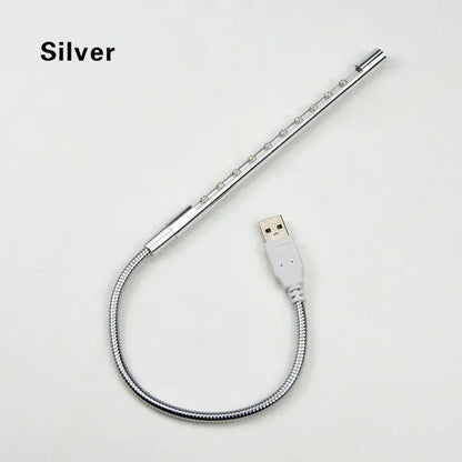 Spiral shaped silver aluminium USB LED desk lamp bent on a wooden desk.