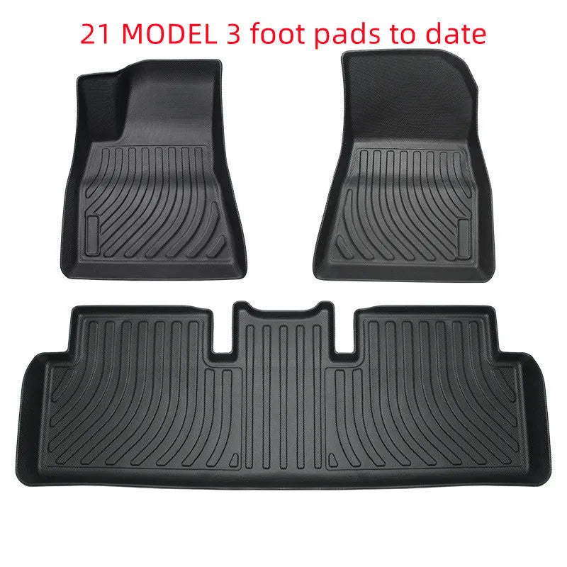 Custom black rubber floor mats fitted in a Tesla Model 3, showing deep grooves and raised edges.