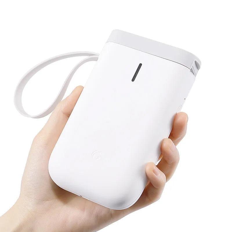 D11 black Bluetooth thermal label printer on a desk next to a smartphone showing the label design app
