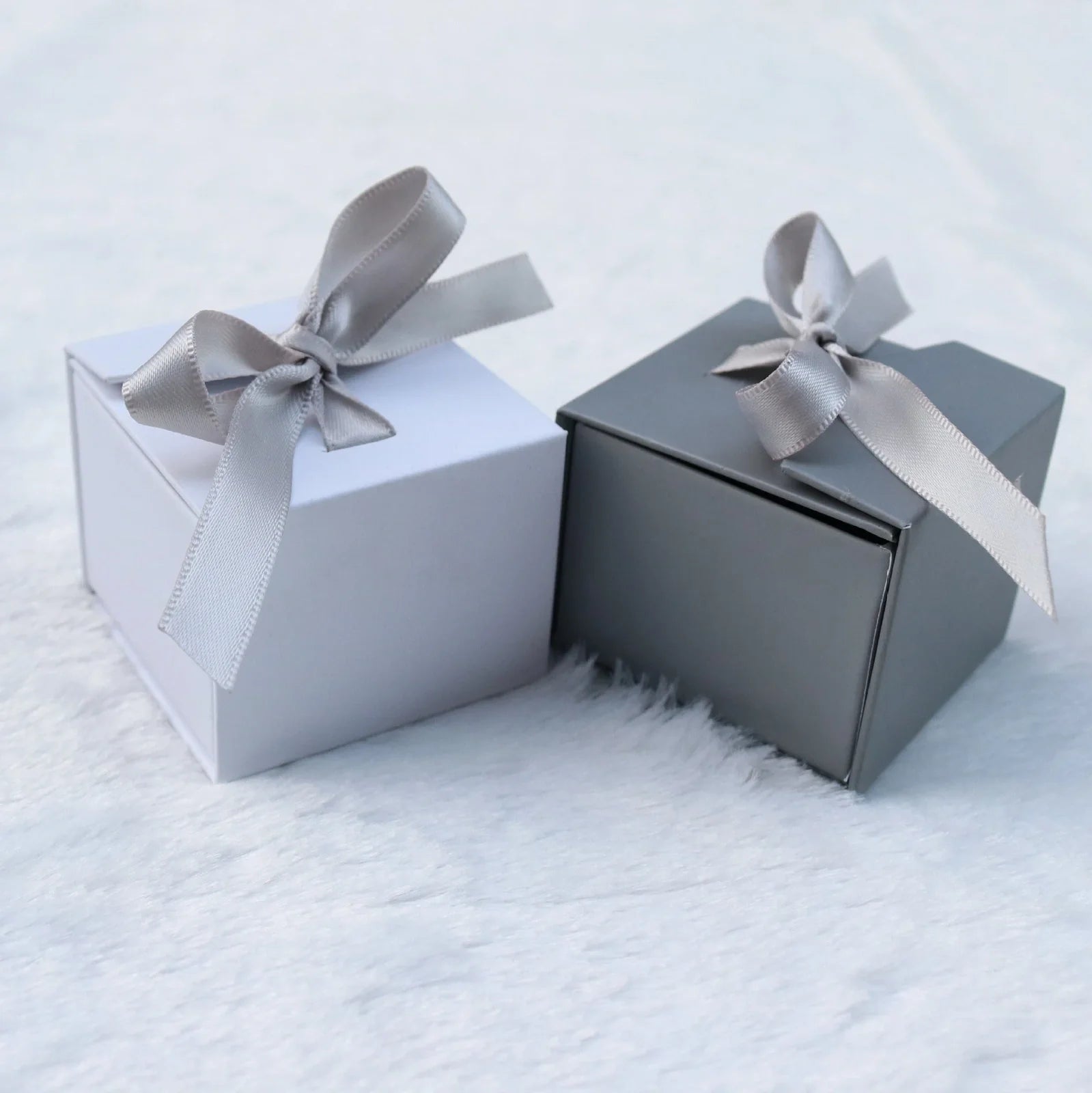 Grey square jewellery box with white ribbon bow measuring 5x5x4cm with sponge-lined interior