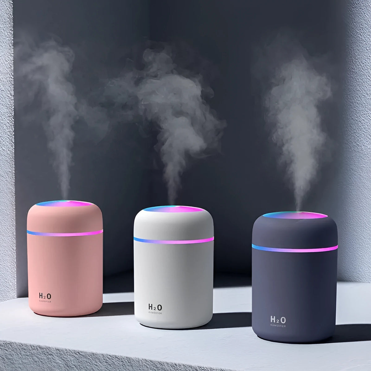 Pink USB desktop humidifier with LED lights and water tank on wooden desk