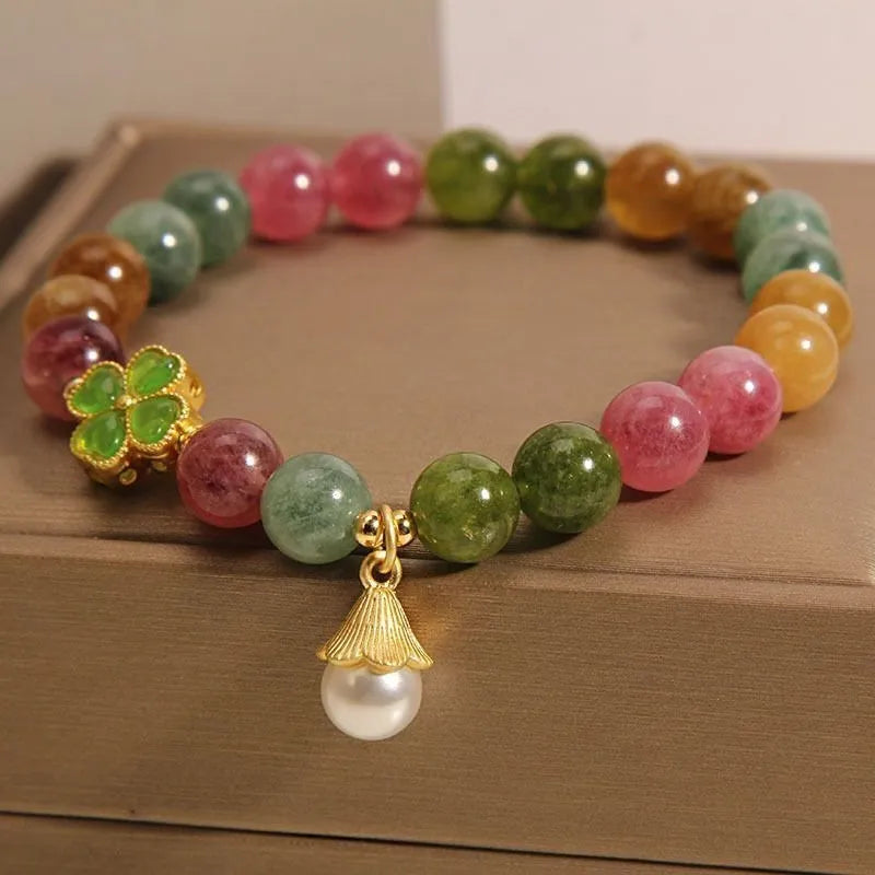 Colourful mixed-material women's bracelet with a four-leaf clover charm and a pearl pendant on a geometric chain.