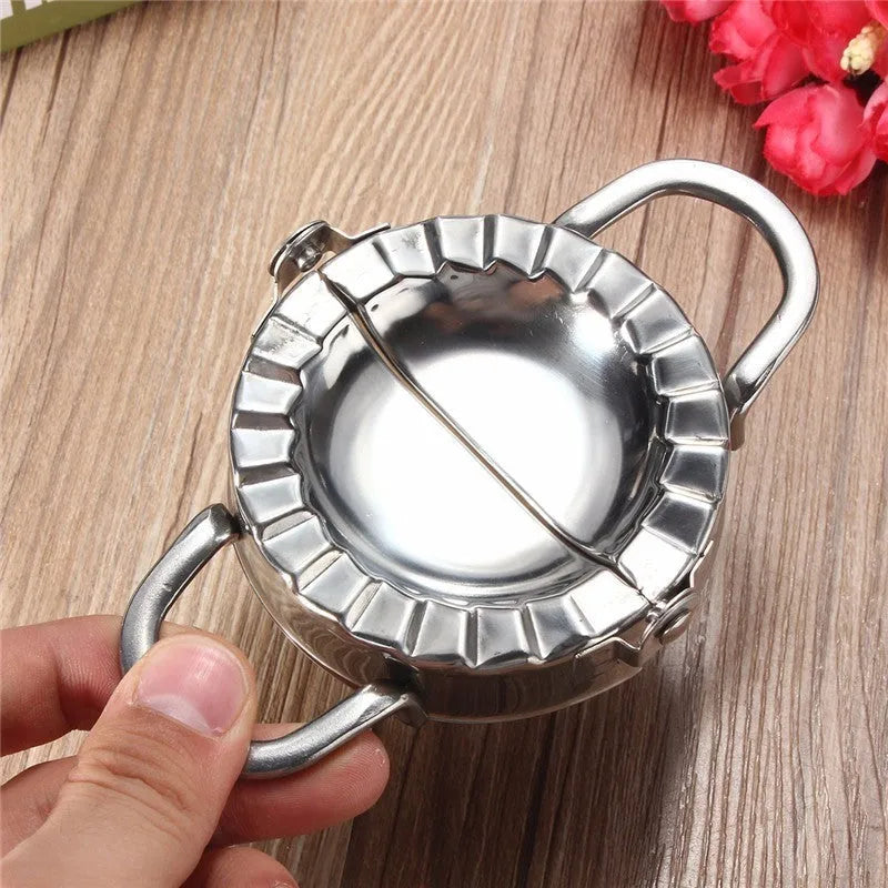 Stainless steel dumpling mould and rectangular dough cutter on a kitchen surface.