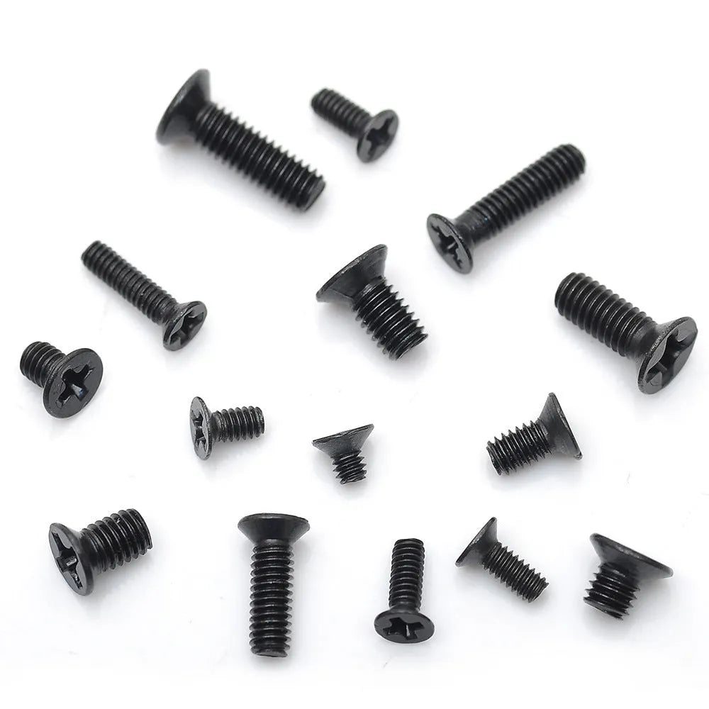 Black laptop machine screws with countersunk cross heads, shown in loose pile and close-up