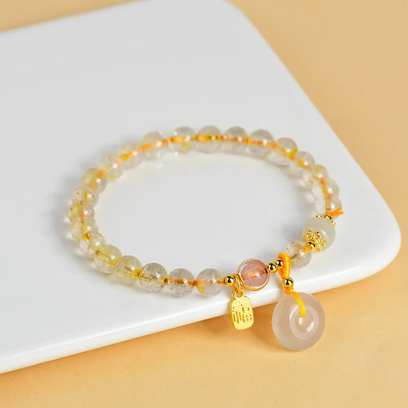 Gold rutilated quartz crystal bracelet with geometric peace buckle pendant and safety clasp