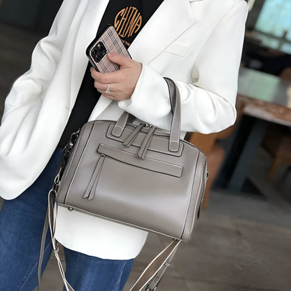 Genuine leather horizontal messenger bag in wine red with shoulder strap and internal zippered compartments.