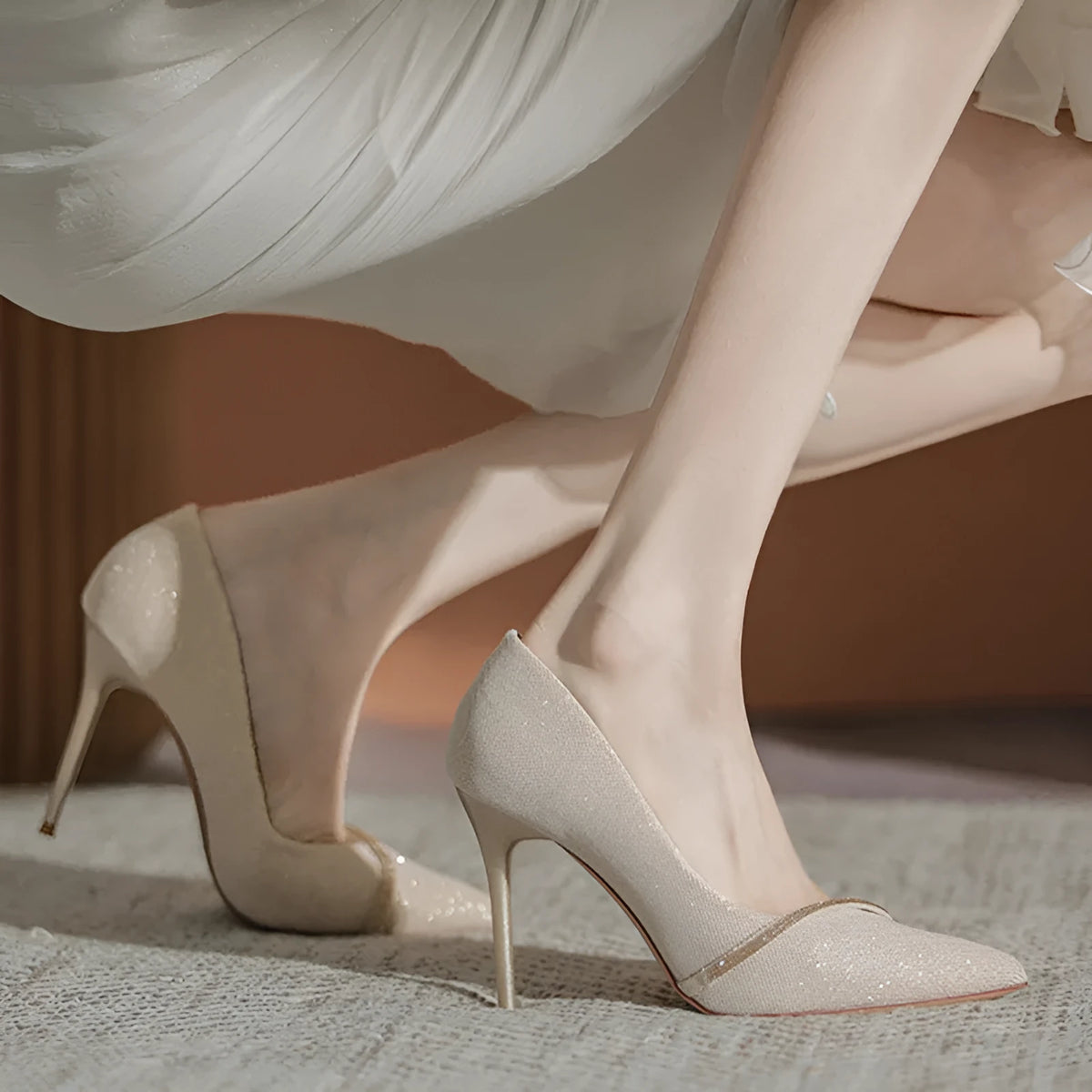 Gold women's stiletto high heels with pointed toe on a plain background.