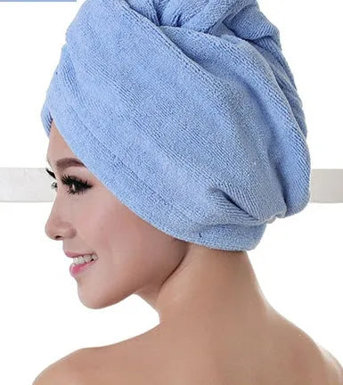 A woman wearing a sky blue microfiber hair dryer cap, with wet hair tucked inside, showing the towel's wrap-around design.
