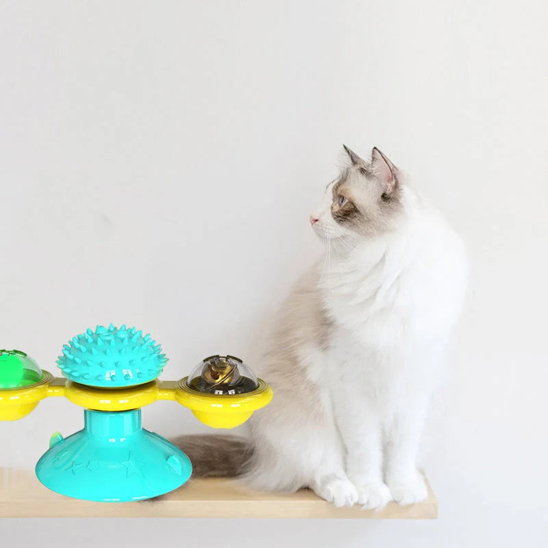 Cat playing with rotating windmill toy featuring luminous balls and suction base