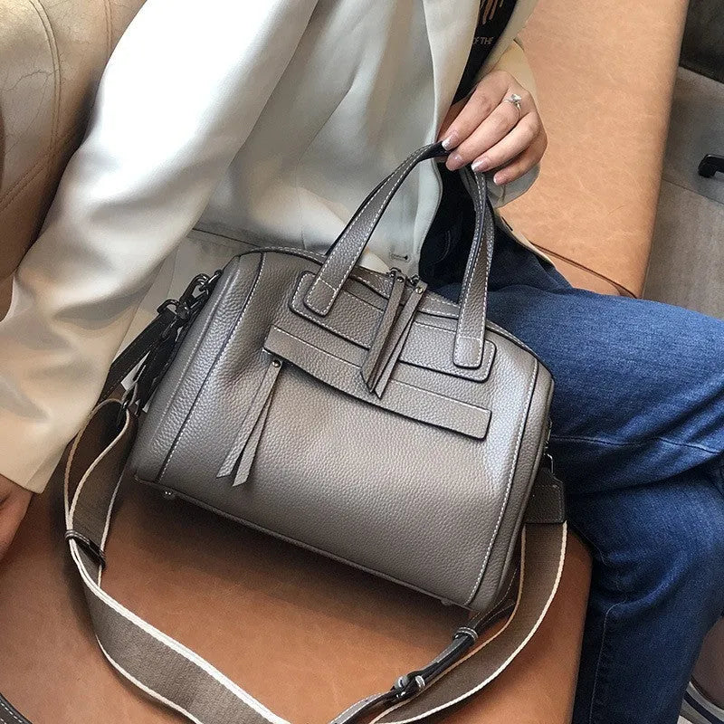 Genuine leather horizontal messenger bag in wine red with shoulder strap and internal zippered compartments.
