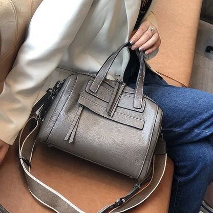 Genuine leather horizontal messenger bag in wine red with shoulder strap and internal zippered compartments.