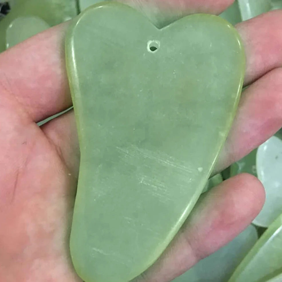Natural green jade beauty massager with roller and scraper tools on white background